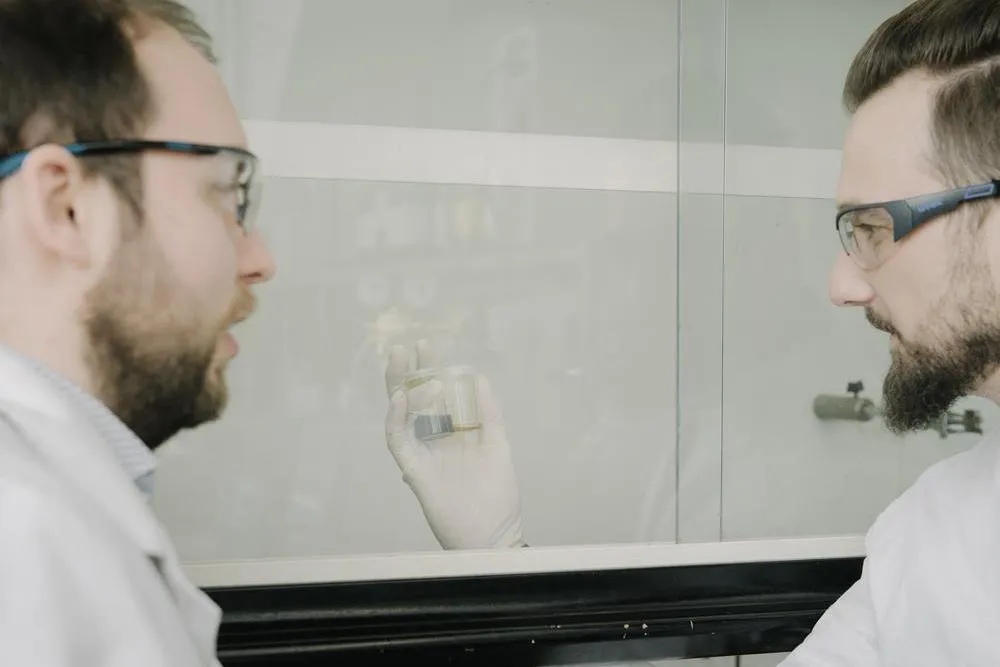 Kevin Carl (right) and his colleague Fabian Roemer (left) examine a sample of the oil fraction produced by pyrolysis.