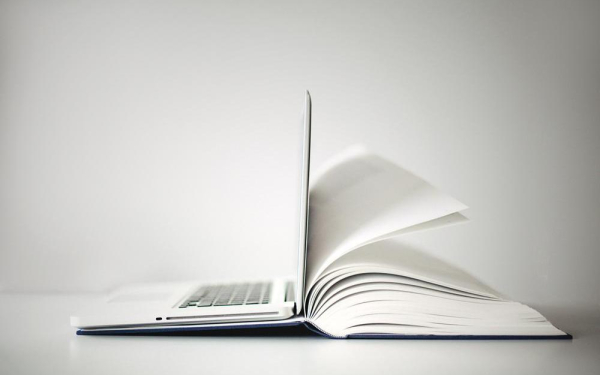 Ein Laptop steht auf einem aufgeklappten Buch