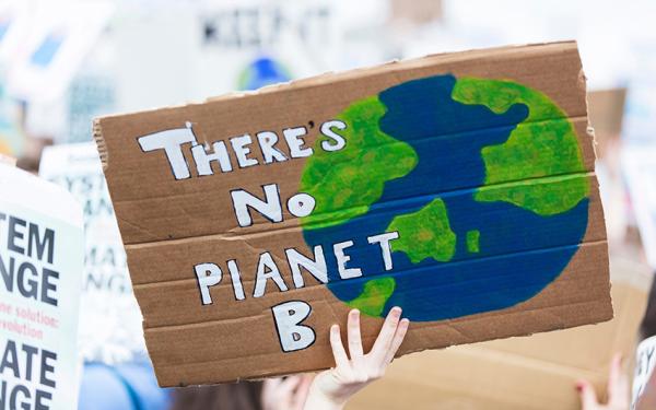 Ein Pappschild wird in die Luft gehalten auf dem steht: "There's no planet B"