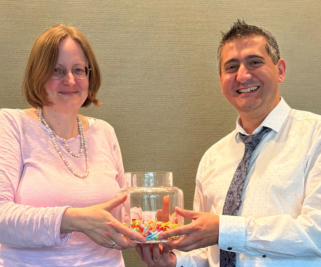 eine Frau und ein Mann mit einem Glas mit bunten Losen