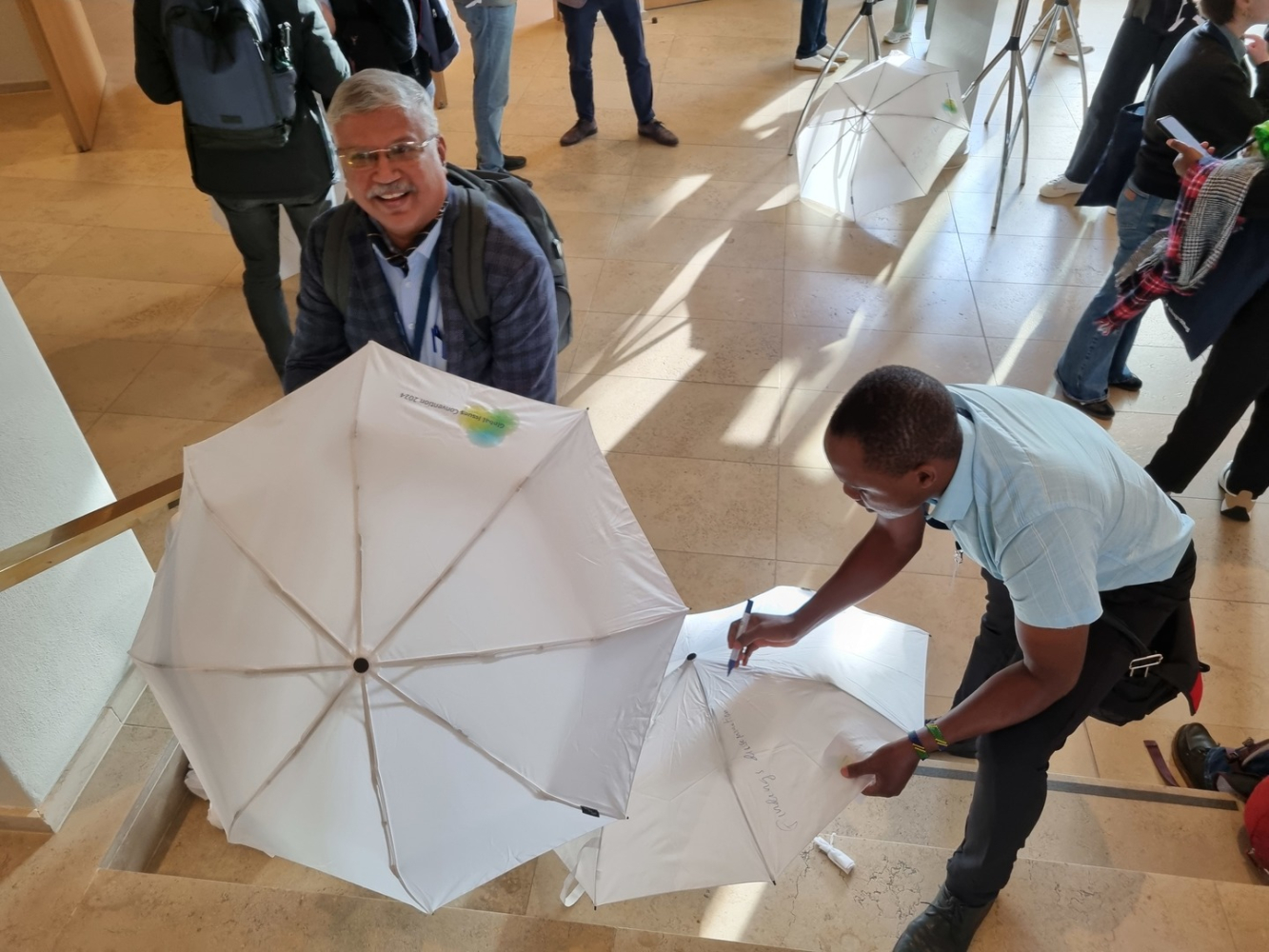 Personen beim Beschriften von weißen Regenschirmen 