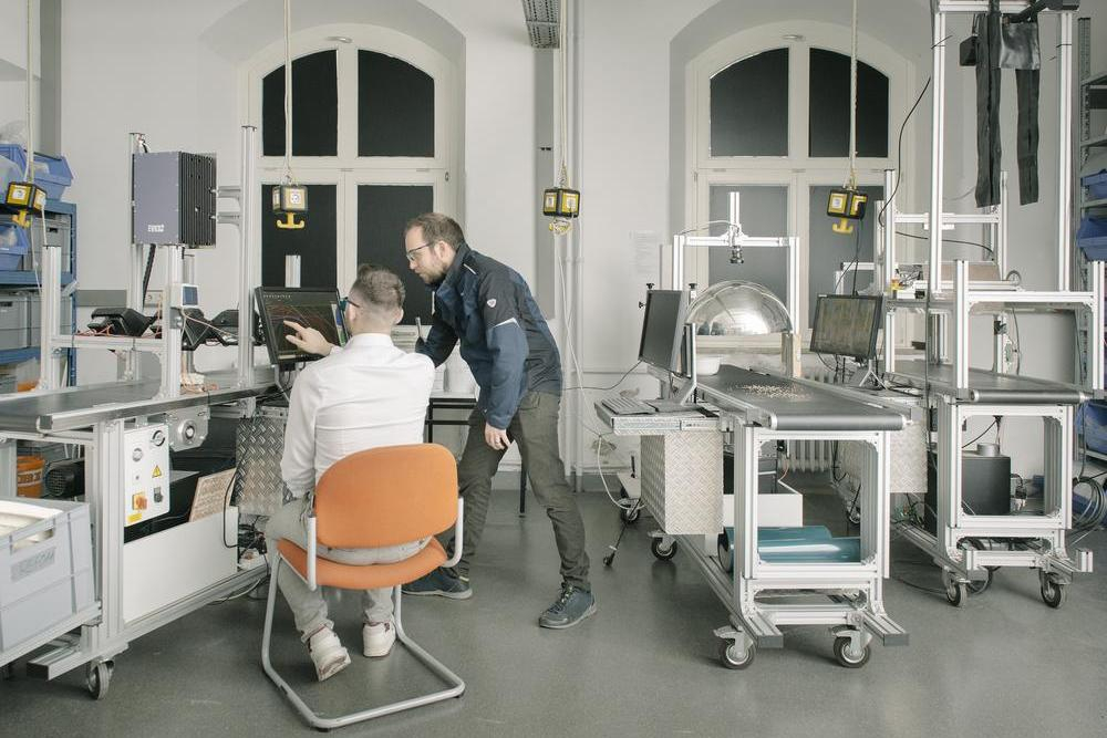 Zwei Männer stehen in einem Labor und schauen gemeinsam auf einen Bildschirm