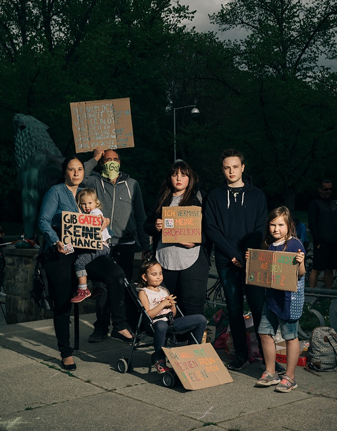 Eine Gruppe von Erwachsenen und Kindern protestieren mit Plakaten gegen die Corona-Maßnahmen. 